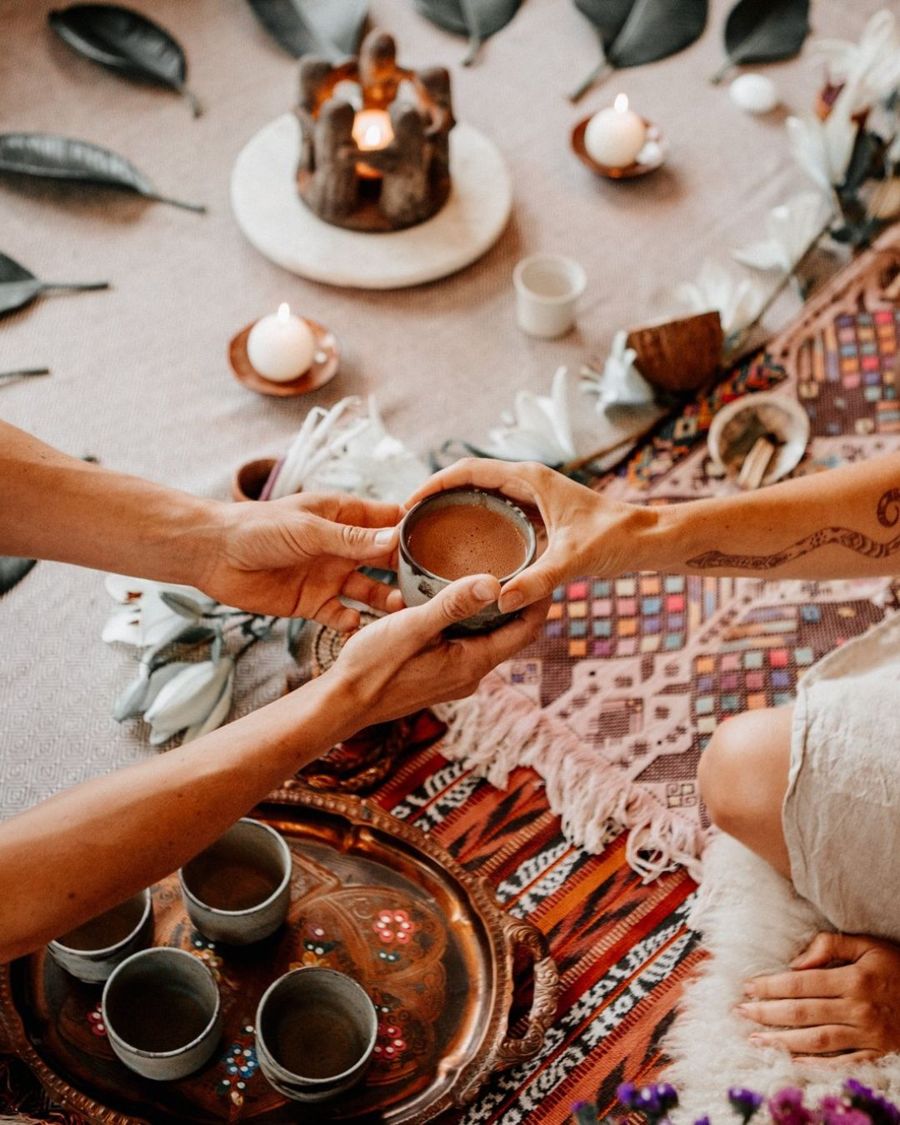 Manos compartiendo una taza en un círculo con velas